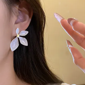 Detailed close-up of vintage white enamel flower stud earrings worn on the ear