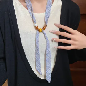 Detail view of high-end blue plaid ribbon necklace with multi-color beads on woman