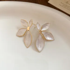Macro detail of elegant retro flower stud earrings featuring pearlescent enamel and gold finish.