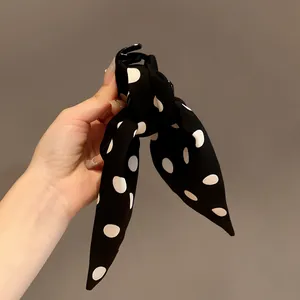 Detail showing a black and white polka dot bow hair claw clip for elegant styling