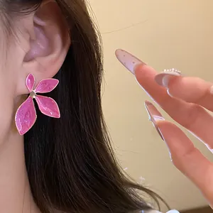 Detailed view of pink drip oil flower stud earring worn on ear