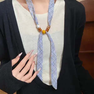 Close-up detail of a women's blue plaid ribbon necklace featuring vibrant decorative beads.