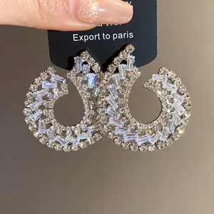 Détail de boucles d'oreilles géométriques en zircon avec pierres baguette et rondes