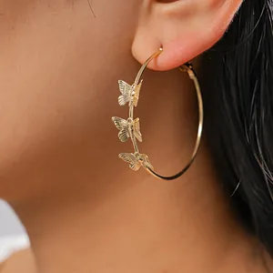 Detailed close-up of a large gold hoop earring featuring three delicate butterfly charms