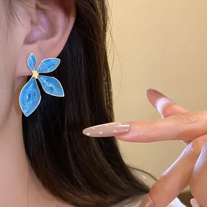 Close-up detail of a vintage blue enamel flower stud earring worn on an earlobe
