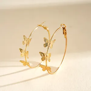 Detailed close-up view of golden metal hoop earrings with delicate butterfly charms