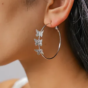 Close-up detail of silver hoop earrings with butterfly charms worn by a model