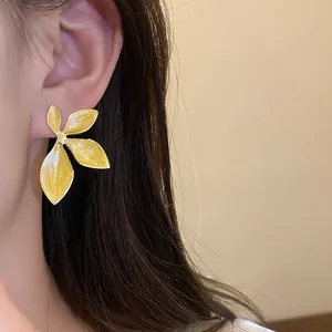 Close-up of a stylish yellow drip oil flower earring worn on an ear for a chic look