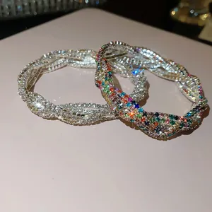 Nahaufnahme von funkelnden silbernen und Regenbogen-Strassarmbändern auf rosa Hintergrund