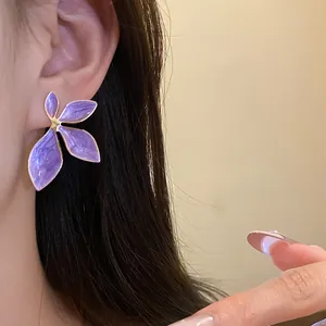 Detailed close-up of a purple enamel floral earring worn on an ear with long dark hair