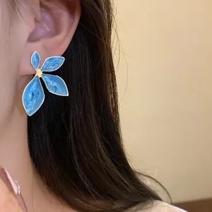 Detailed macro view of elegant blue enamel flower stud earrings with gold-plated edges
