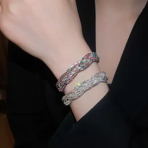 Nahaufnahme von vintage geflochtenen Strassarmbändern in Regenbogen und Silber.