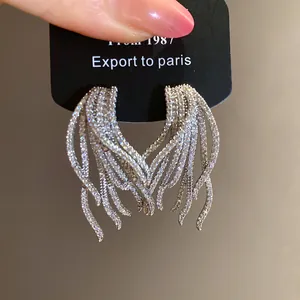 Close-up of silver-plated wing earrings with sparkling zircons on a display card.