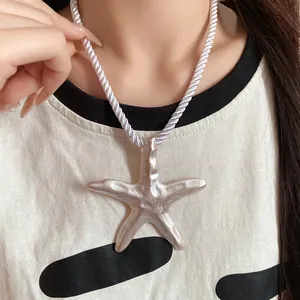 Close-up of large starfish pendant necklace with white twisted rope chain.