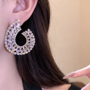 Gros plan détaillé montrant le pavé de zircons sur la boucle d'oreille géométrique.