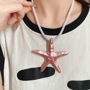 Detail view of a large rose pink starfish pendant necklace with a white twisted silk rope cord.