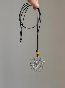 Close-up of vintage silver flower pendant necklace with orange bead and black cord