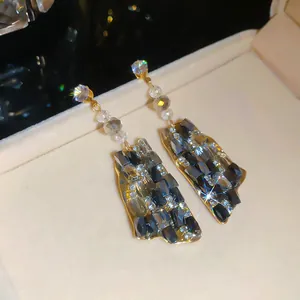 Detalle de pendientes de lujo franceses con cristales gris oscuro y acabado dorado