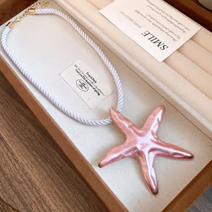 Detailed view of a pink starfish pendant necklace with a white silky rope chain
