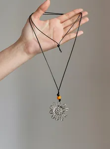 Detail shot of a vintage ethnic style necklace with a flower pendant held by hand.