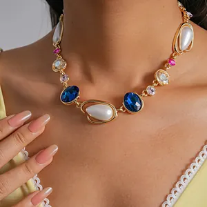 Close-up of vintage gold necklace with blue crystals and pearls worn by a model.
