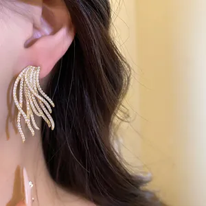 Detailed view of elegant 18k gold plated cubic zirconia feather-shaped earrings on model's ear.