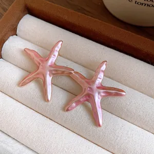 Detailed macro view of elegant pink starfish enamel earrings resting in a jewelry box