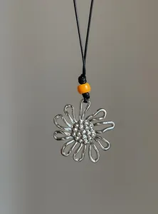 Detail view of retro silver pleated flower pendant necklace with orange bead accent