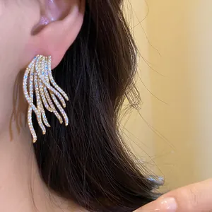 Detailed view of 18k gold plated silver needle zirconia tassel earrings worn on an ear.