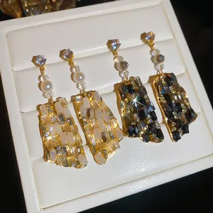 Detalle de pendientes de lujo franceses con cristales y pedrería en blanco y negro oro