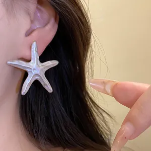 Detailed view of elegant silver starfish earrings featuring a unique textured finish on ear