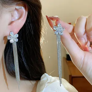 Close-up detail of elegant 18k gold plated zircon flower earrings with long silver tassels