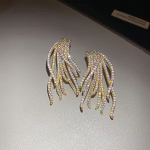 High-definition detail of 18k gold plated silver needle earrings with shimmering zircon tassels.