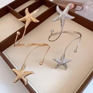 Detailed close-up of stylish metal starfish arm cuff bracelets with a wrinkled texture
