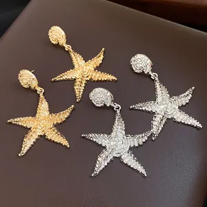 Dettaglio macro di orecchini a stella marina in oro e argento con finitura testurizzata