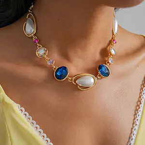 Detail view of vintage gold necklace with blue gems and teardrop pearls on model