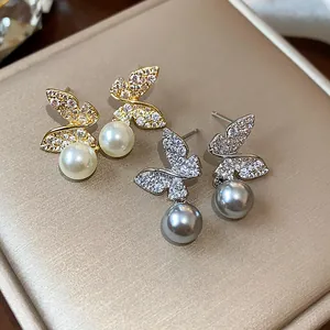 Detailed macro view of delicate butterfly pearl stud earrings in gold and silver finishes