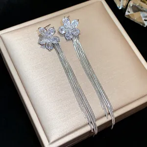 Close-up detail of elegant silver zircon flower earrings with long tassels on a gift box