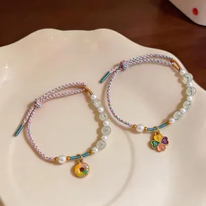 Elegant handmade braided pearl bracelet featuring colorful donut and floral charms on a dish