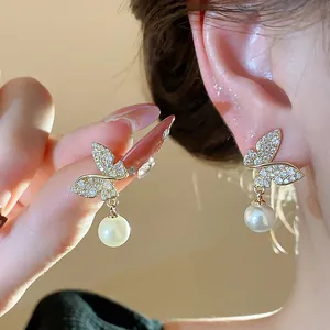 Detailed view of elegant gold butterfly pearl earrings with sparkling rhinestones