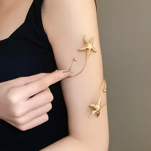 Close-up of a gold pleated metal starfish arm cuff worn on a woman's upper arm
