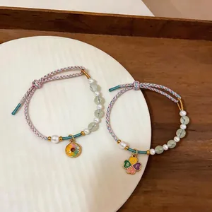 Handmade braided pearl and bead bracelet featuring a clover charm with colorful cord