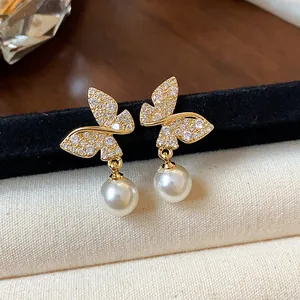 Detailed view of elegant gold butterfly earrings with crystals and white pearl drops