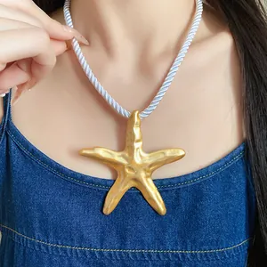 Close-up detail of a gold starfish pendant necklace featuring a white twisted rope cord