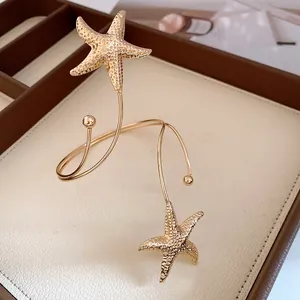 Detailed view of a gold metal starfish open arm cuff featuring a crinkle texture design