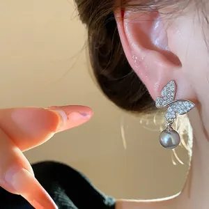 Detailed view of elegant butterfly pearl stud earrings worn on an ear, French style dainty jewelry