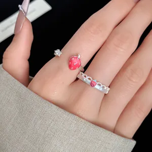 Detailed view of dainty silver-colored strawberry and star open rings on a model finger