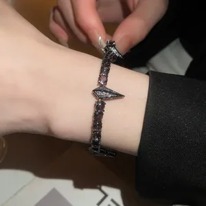 Close-up of a punk-style black bracelet featuring purple zircons and a geometric clasp