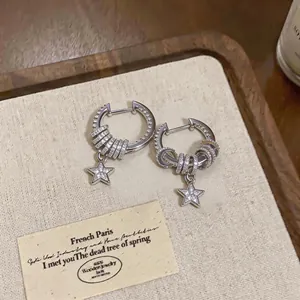 Close-up of silver hoop earrings featuring pavé zircon rings and dangling star charms