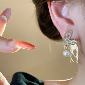 Close-up of elegant butterfly earrings with sparkling crystals and a delicate hanging pearl.